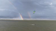 Prachtige beelden van surfers op het water tijdens dubbele regenboog